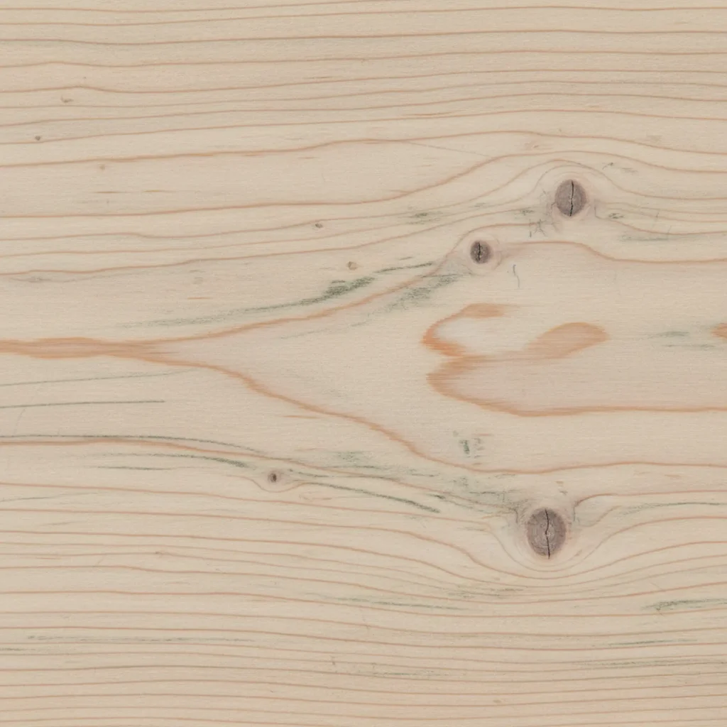Light natural wood plank with horizontal grain lines, several dark knots, and faint green and orange streaks.